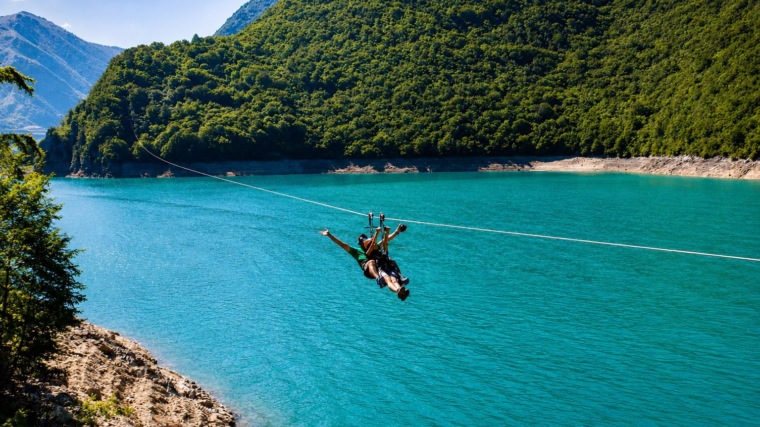 Zip-line above the turquoise water of Piva Lake and green mountain slopes